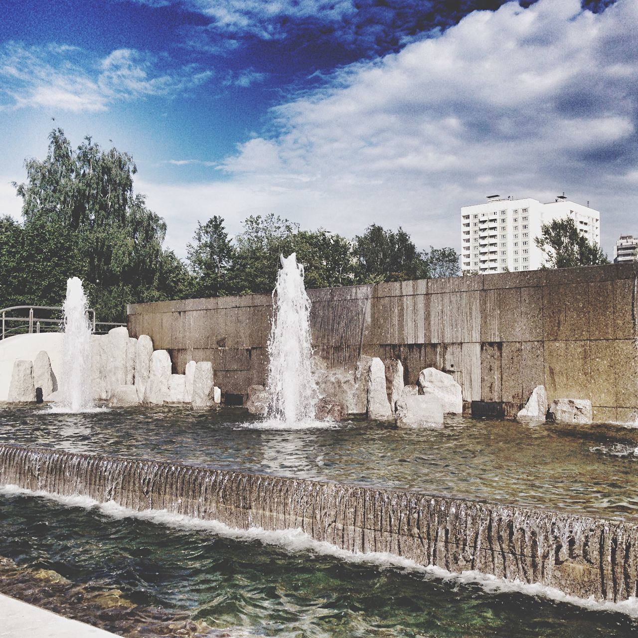 water, fountain, motion, sky, splashing, built structure, architecture, flowing water, spraying, building exterior, cloud - sky, waterfront, long exposure, famous place, sculpture, waterfall, travel destinations, statue, tree, tourism