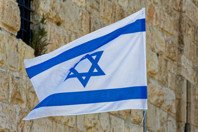 Close-up of israeli flag waving against stone wall