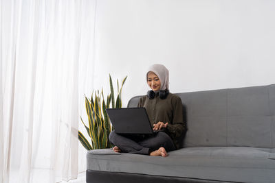 Young man using laptop while sitting on sofa at home
