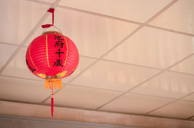 Low angle view of lantern hanging against orange wall