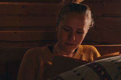 Close-up of young woman reading book at home