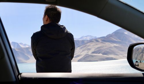 Rear view of man photographing in car