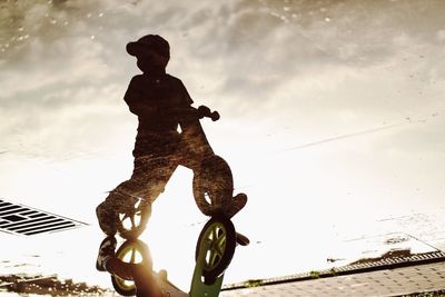 Reflection of boy riding bicycle