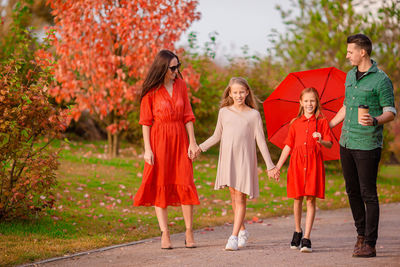 Rear view of women standing with red umbrella