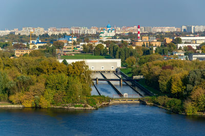 Bridge over river by buildings in city against sky