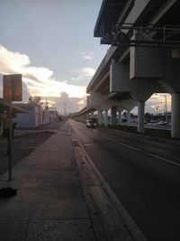 Empty road along buildings at sunset