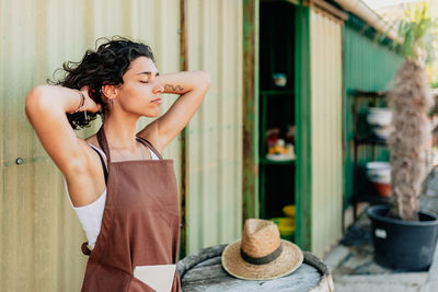 Young woman looking away while standing outdoors