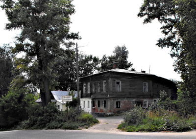 Road amidst trees and houses against clear sky