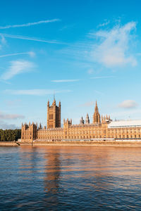 View of buildings by river against sky in city