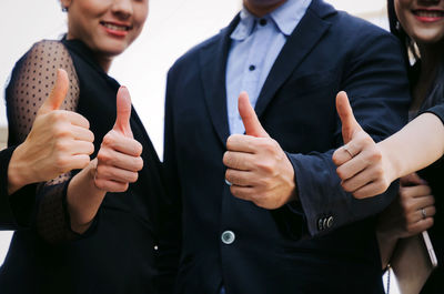 Colleagues gesturing thumbs up sign in office