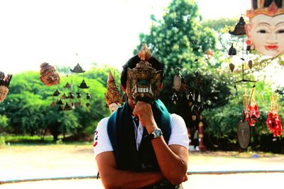 Man holding mask against sky