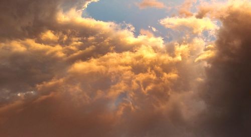 Low angle view of sunlight streaming through clouds