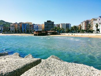 Scenic view of sea and buildings against clear sky