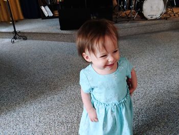 Cute smiling baby girl looking away while standing on floor