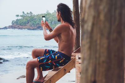 Man sitting on wooden chair at beach