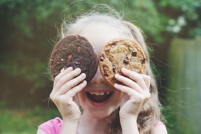 Close-up of cut girl holding cookies while standing outdoors