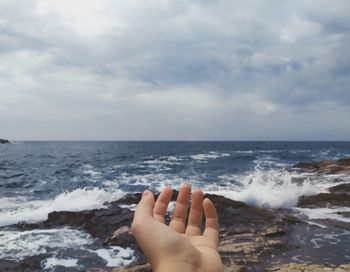 Midsection of person on sea against sky