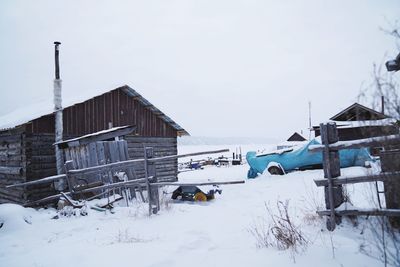 Abandoned house on snow covered field against sky