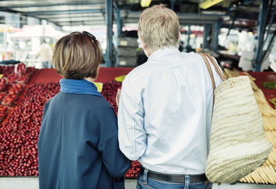 Rear view of senior couple buying fruits at market