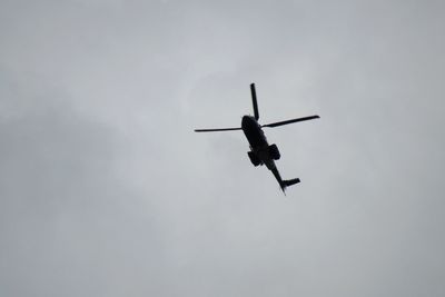 Low angle view of silhouette helicopter flying against sky