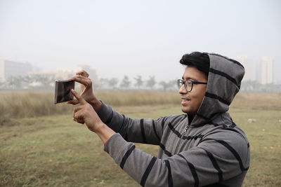 Man photographing with camera on field against sky