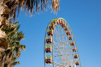 Low angle view of ferris wheel against clear blue sky