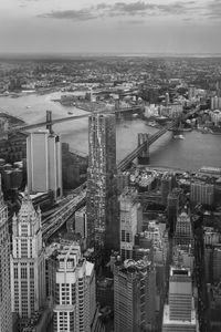 High angle view of buildings by river against sky in city