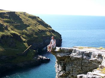 Scenic view of sea by cliff against sky