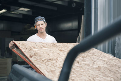 Carpenter loading wooden planks in pick-up truck