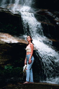 Portrait of young woman standing in waterfall