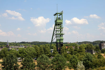 Tower amidst trees and buildings against sky