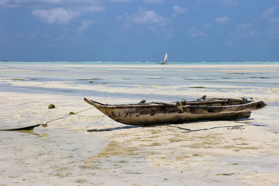 Boat moored on beach against sky