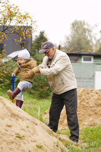 Grandfather assisting grandson in climbing rock