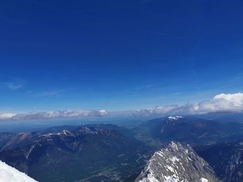 Aerial view of snowcapped mountains against blue sky