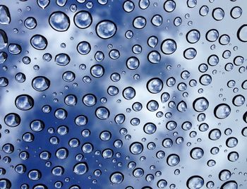 Full frame shot of wet glass against blue sky