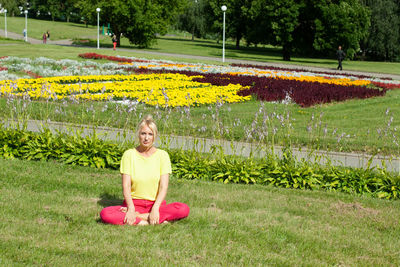 Portrait of smiling woman sitting on grass in park