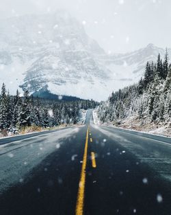 Road by mountains against sky during winter