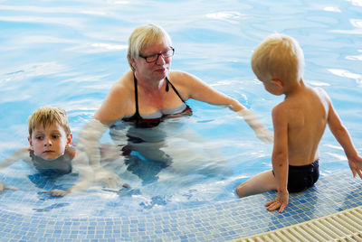 High angle view of grandmother with grandsons swimming in pool