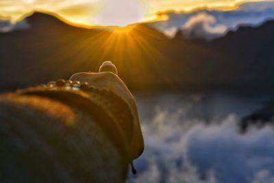 Close-up of water drops on rock against sky during sunset