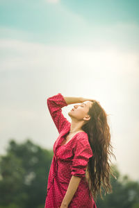 Portrait of smiling young woman standing against sky