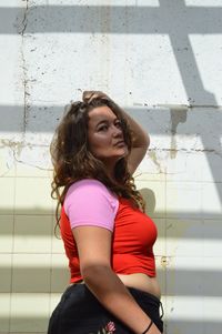 Portrait of beautiful young woman standing against wall