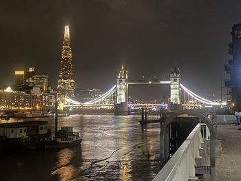 Illuminated bridge over river against sky at night