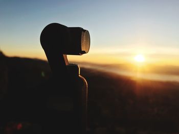 Close-up of silhouette camera on field against sky during sunset