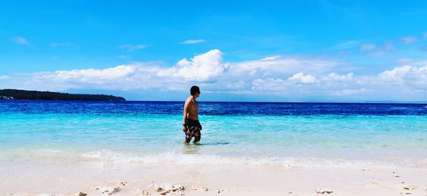 Rear view of man on beach against sky