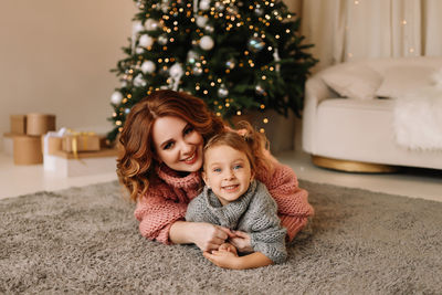 Portrait of cute girl playing with christmas tree at home