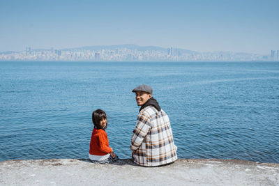 Rear view of woman looking at sea against clear sky