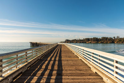 View of boardwalk leading towards sea against sky