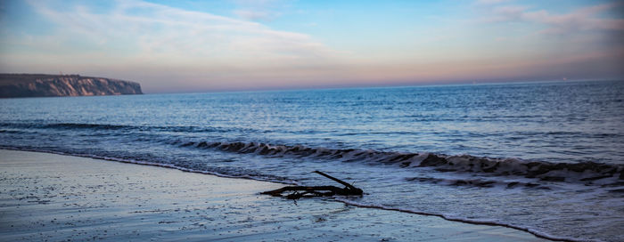 Scenic view of beach against sky at sunset