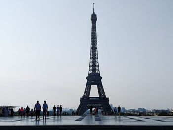 Early summer morning view of the eiffel tower with people in distance reflected on the ground.