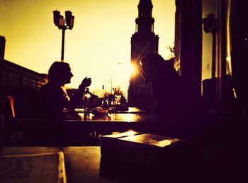 Silhouette of woman sitting at sunset